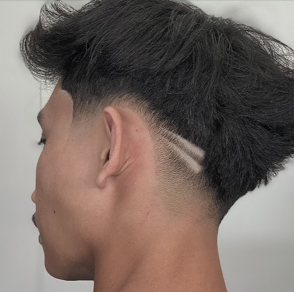 Close-up of a sharp fade haircut with a shaved line design above the ear