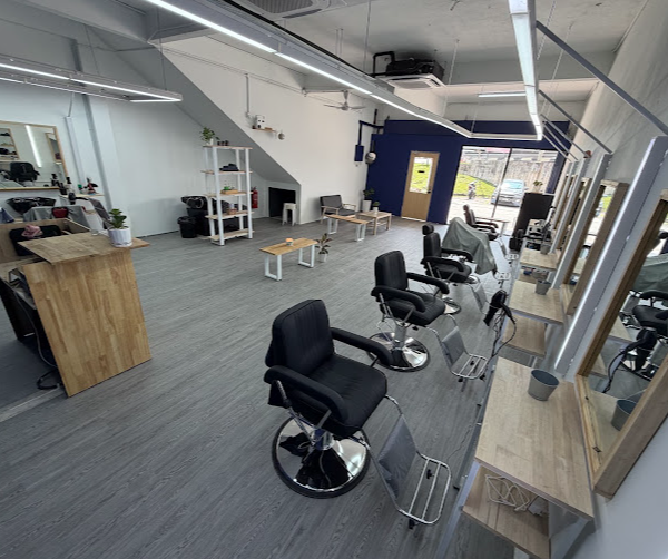 Row of black barber chairs and mirror stations inside Sizzer Barbershop Kajang, with navy accent wall